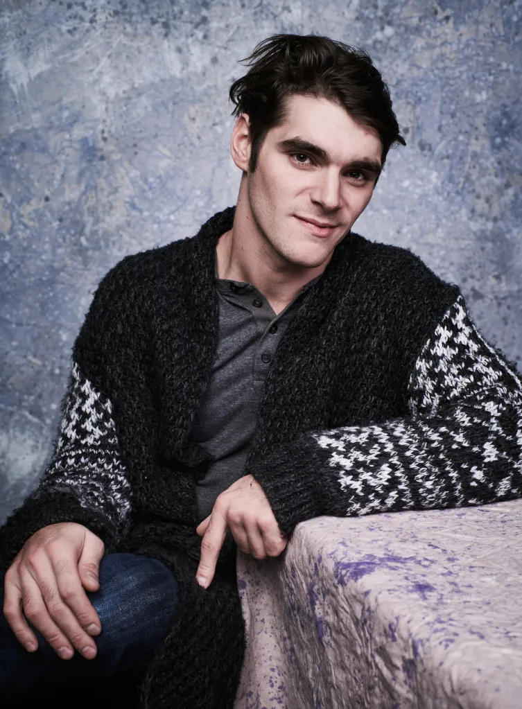 RJ Mitte posing for a portrait in a dark cardigan.