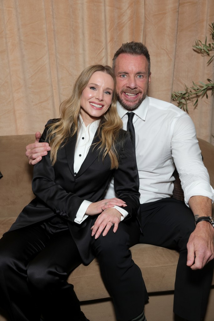 Kristen Bell and Dax Shepard pose together, smiling, on a couch.