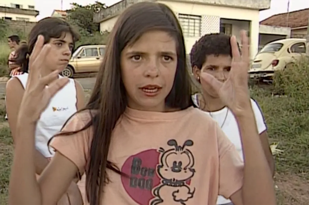 Valquiria Silva gestures with her hands while speaking outdoors, with Liliane Silva and Katia Andrade visible in the background.