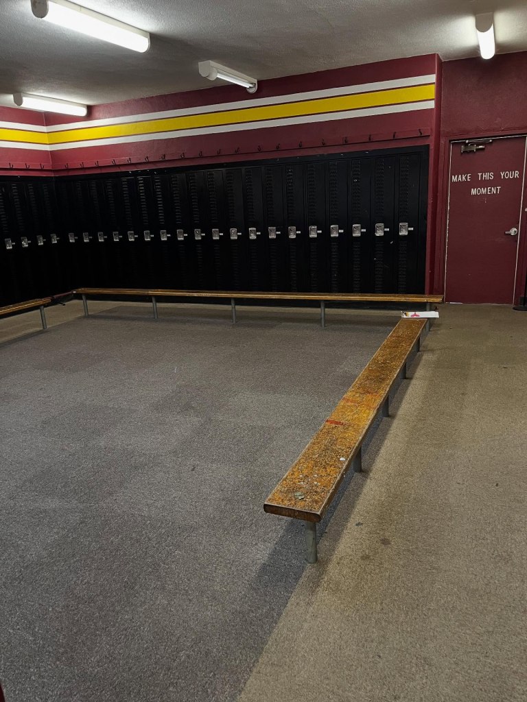 Piner High School locker room with black lockers, wooden benches, and a red door with the words 