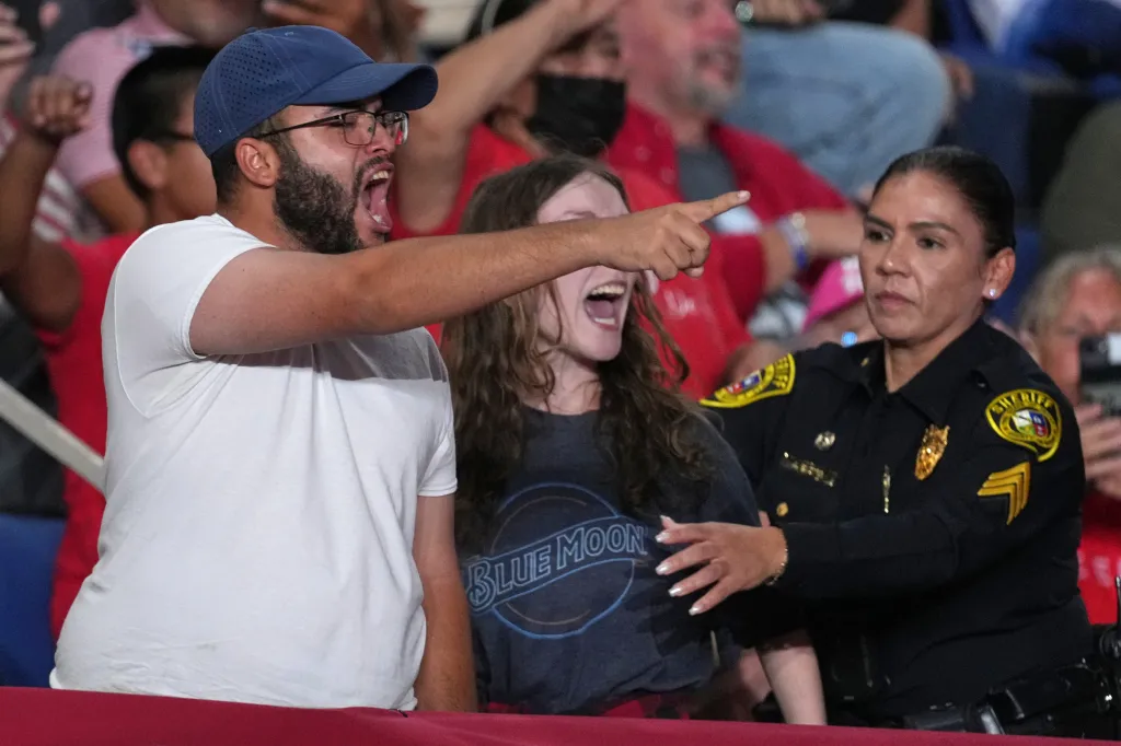 Police remove protesters as Donald Trump speaks at a campaign rally.