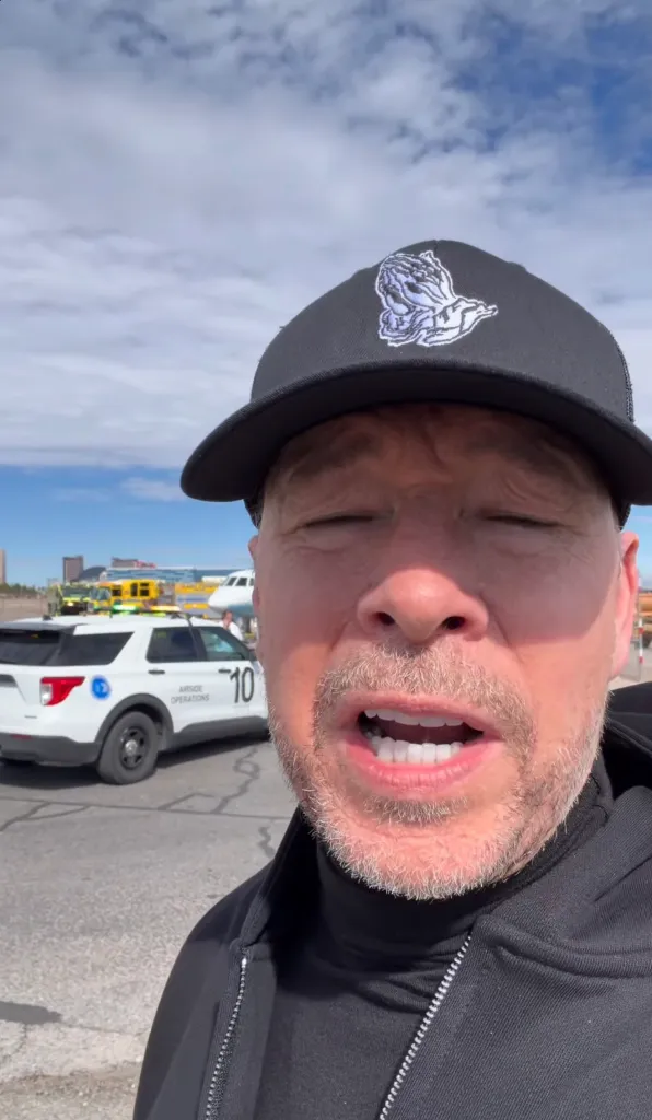 Donnie Wahlberg in front of an emergency vehicle after a private jet skidded off the runway.