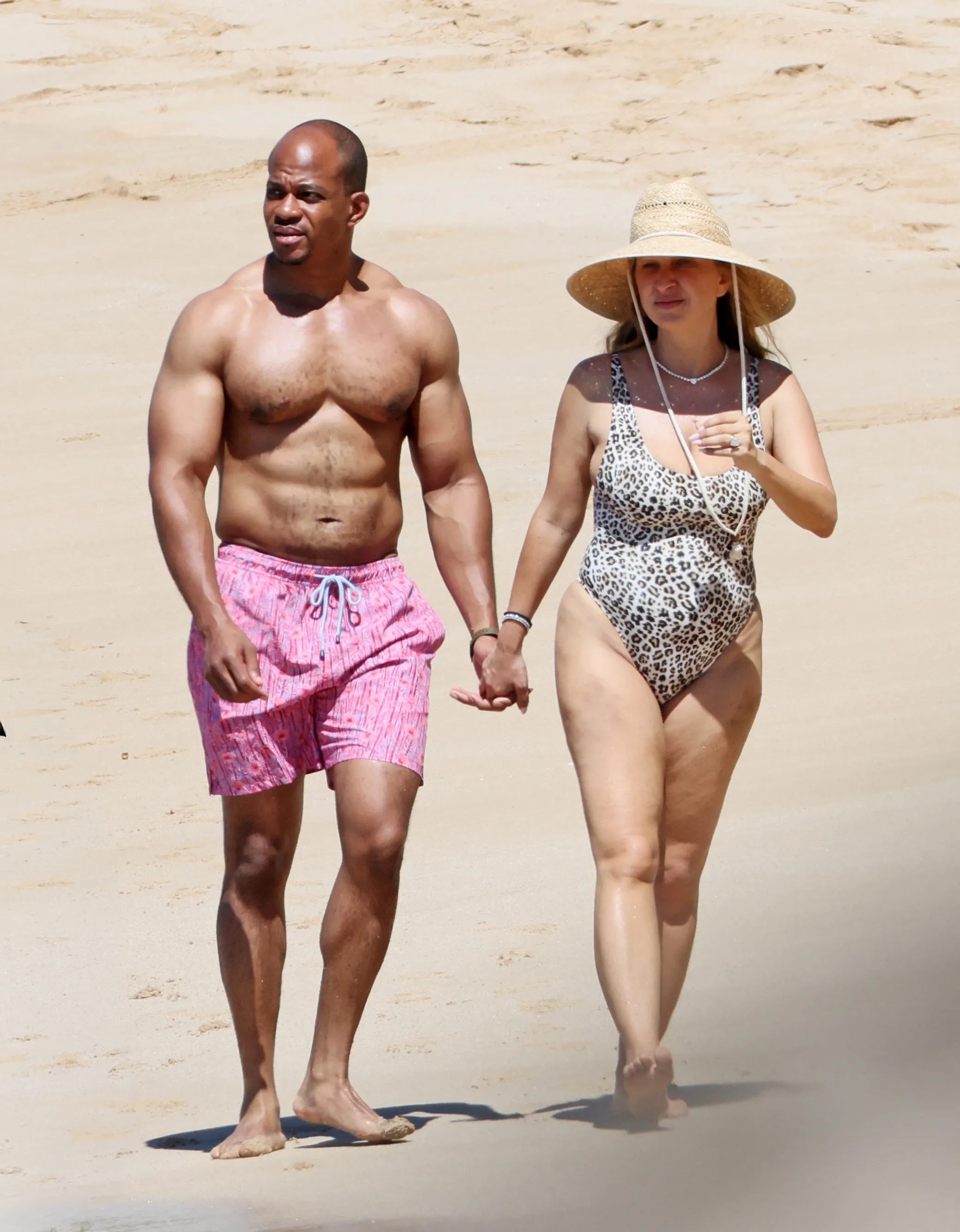 Jennifer Meyer and new husband Geoffrey Ogunlesi holding hands on a Hawaii beach.