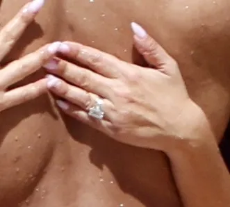 Jennifer Meyer's hand showing a large diamond ring while hugging Geoffrey Ogunlesi.