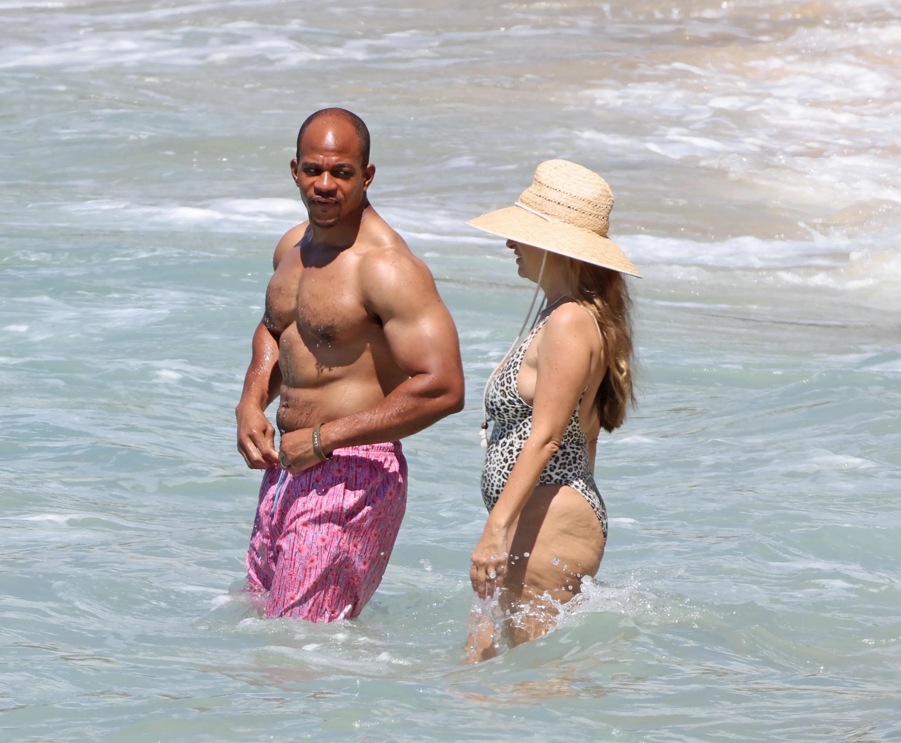 Jennifer Meyer and Geoffrey Ogunlesi wade in the water at a beach in Hawaii.