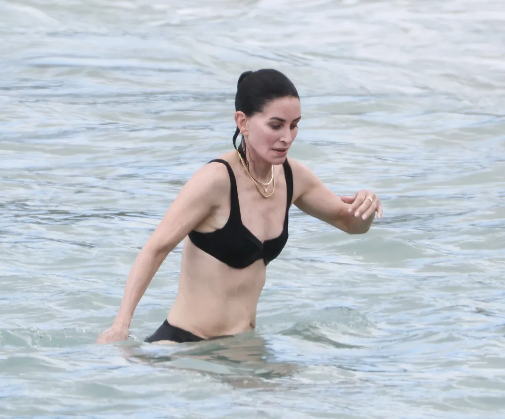 Courteney Cox wearing a black bikini in the ocean during a trip to Hawaii.