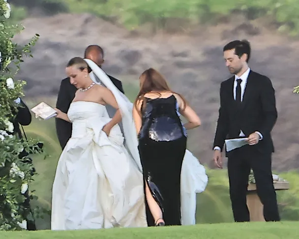 Jennifer Meyer in a wedding dress alongside Geoff Ogunlesi and Tobey Maguire in suits.
