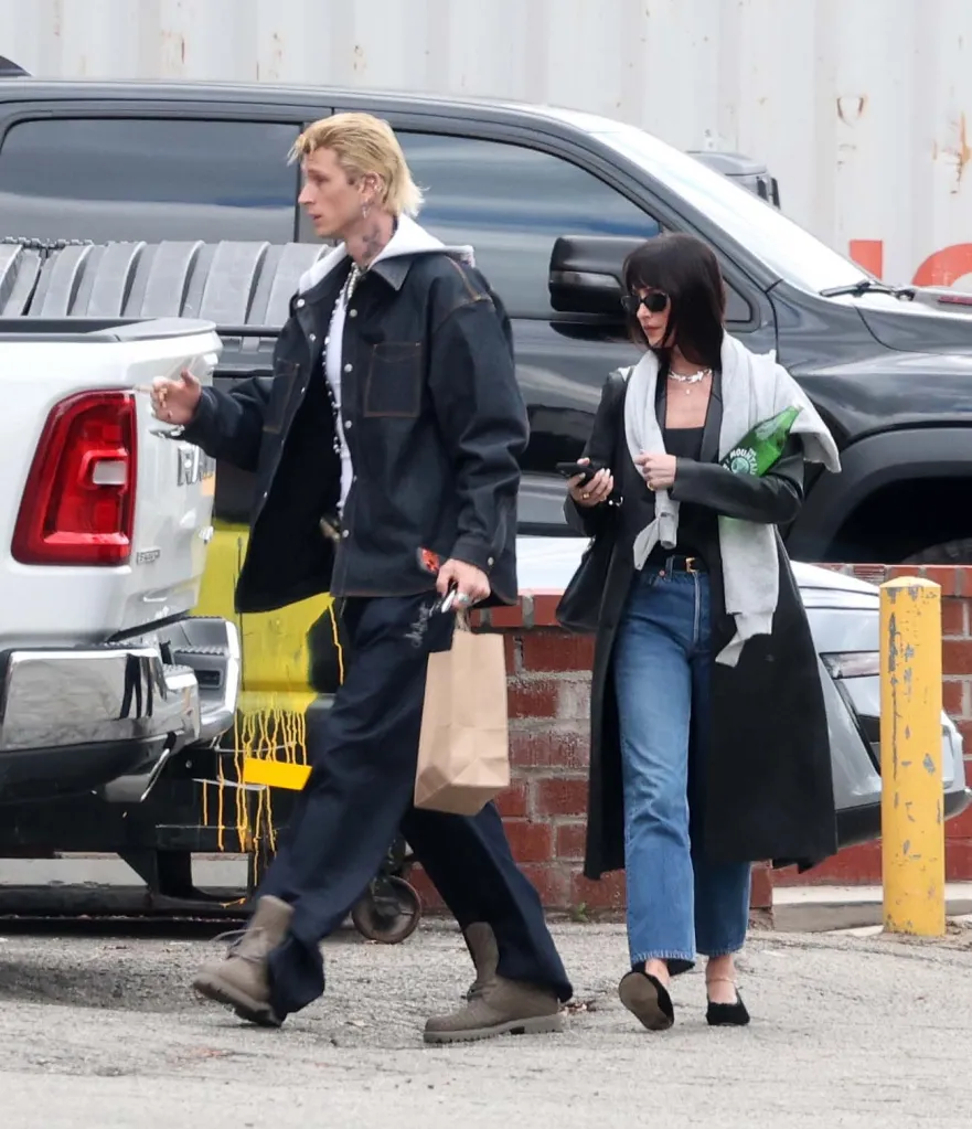 Dakota Johnson and Machine Gun Kelly walk together through a parking lot after leaving a studio.