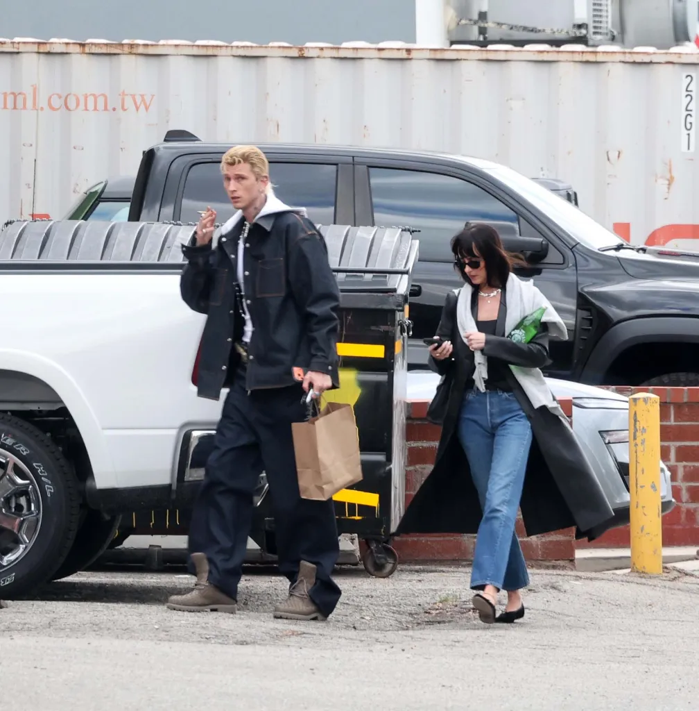 Dakota Johnson and Machine Gun Kelly walk side-by-side through a parking area after leaving a studio in Los Angeles.