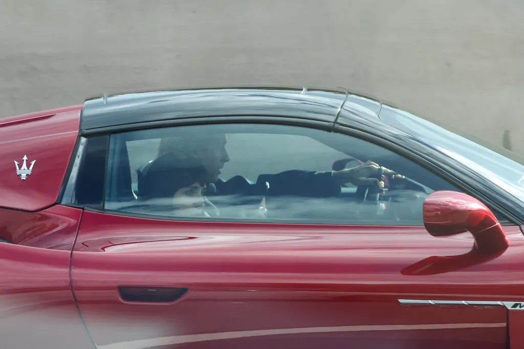 Dakota Johnson and Machine Gun Kelly inside a red sports car.