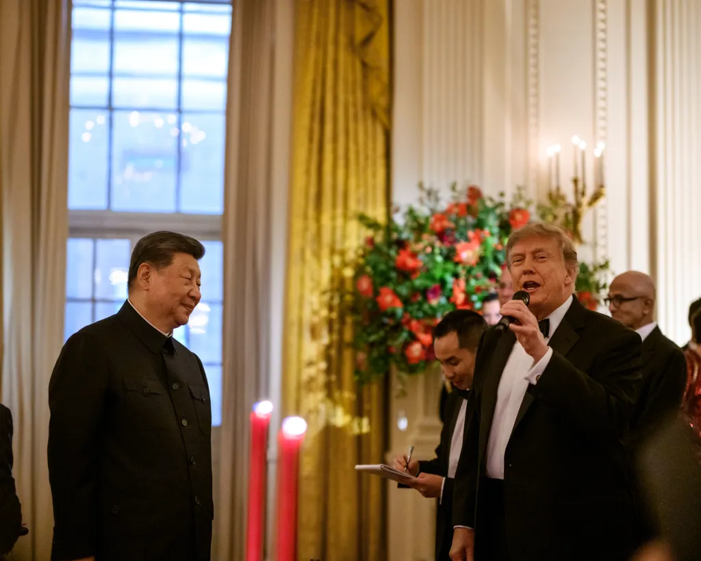 President Donald J. Trump speaks into a microphone while President Xi Jinping of China looks on during a State Dinner in the East Room of the White House.