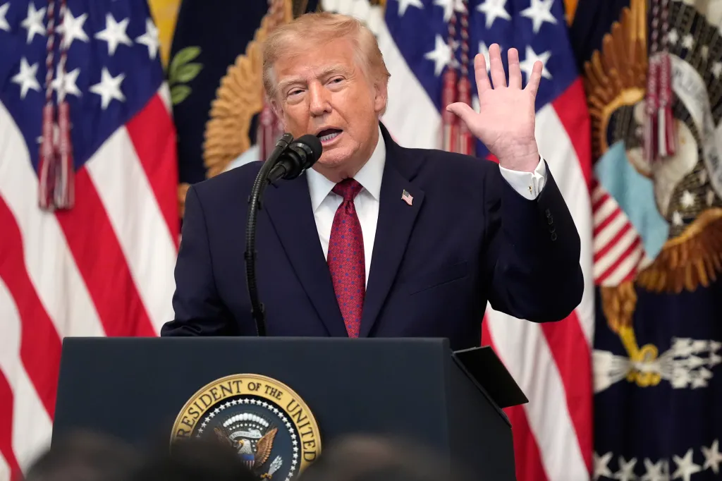 President Donald Trump speaks at a podium with American flags in the background.
