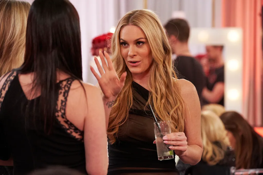 Leah McSweeney talking to someone at a party while holding a drink.