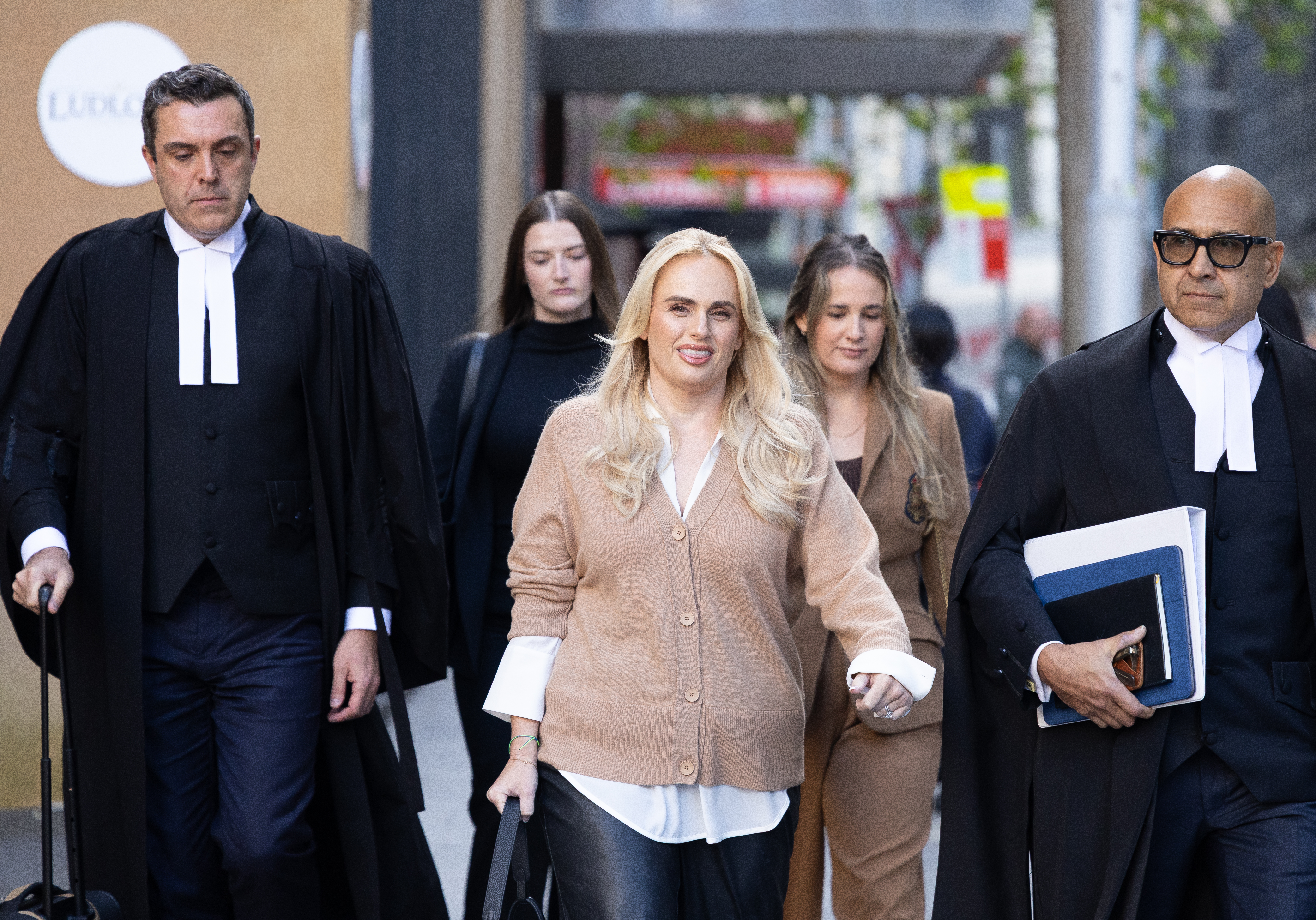 Rebel Wilson arrives at the Federal Court in Sydney, flanked by legal representatives.