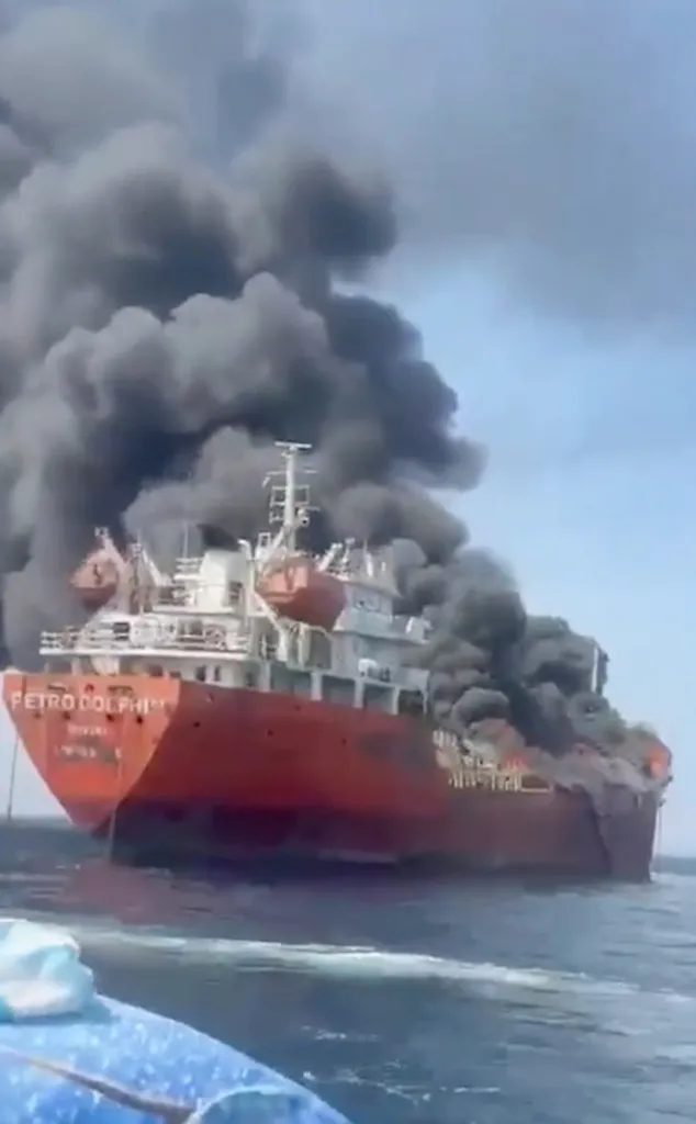 The red-hulled oil tanker MT Petro Dolphin on fire, with thick black smoke billowing from its deck.