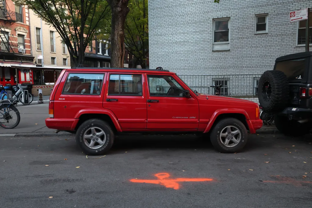 A red Jeep Cherokee Classic parked on a city street.