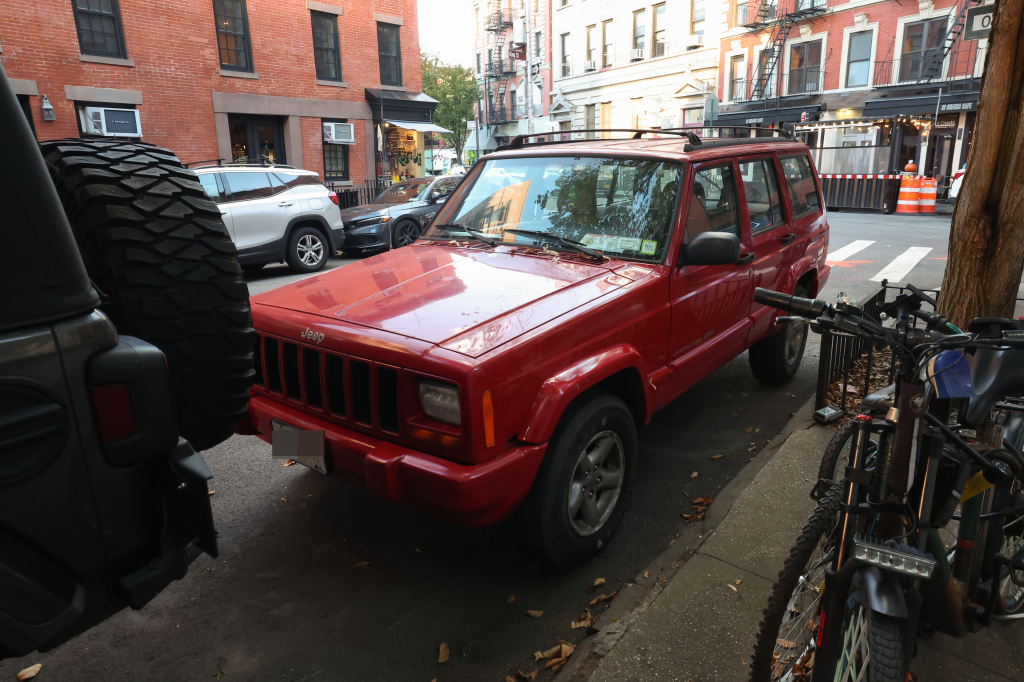 A red Jeep Cherokee parked on a city street.