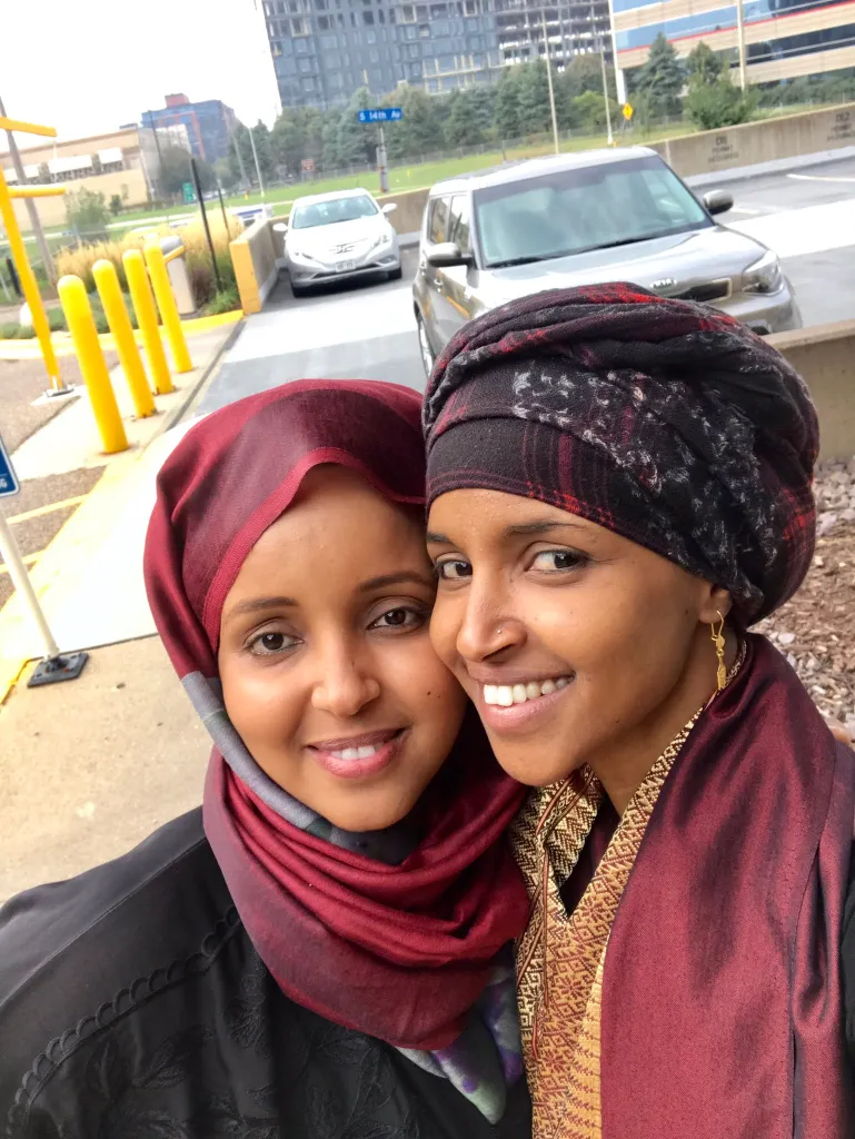 Sahra Noor, left, and Ilhan Omar smiling together outdoors.