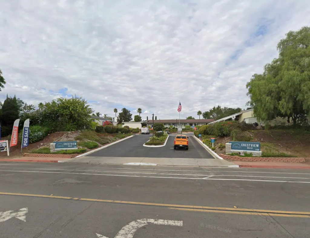 Entrance to the Crestview Hills Mobile Home Park with signage and an orange truck driving up the drive.
