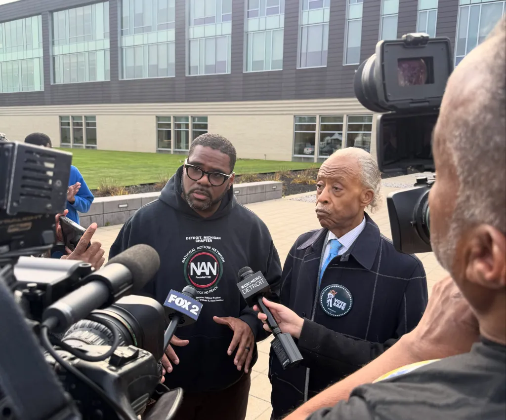 Rev. Charles E. Williams and Rev. Al Sharpton surrounded by reporters and cameras.