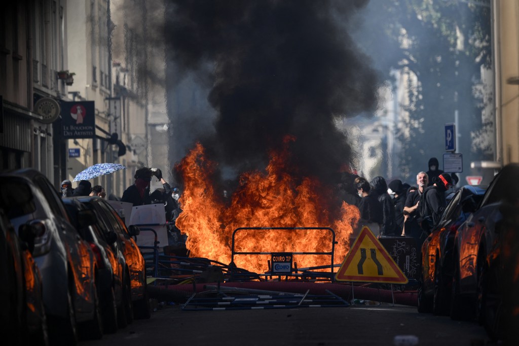 Riot police observe a fire at a makeshift barricade during student protests in Lyon.