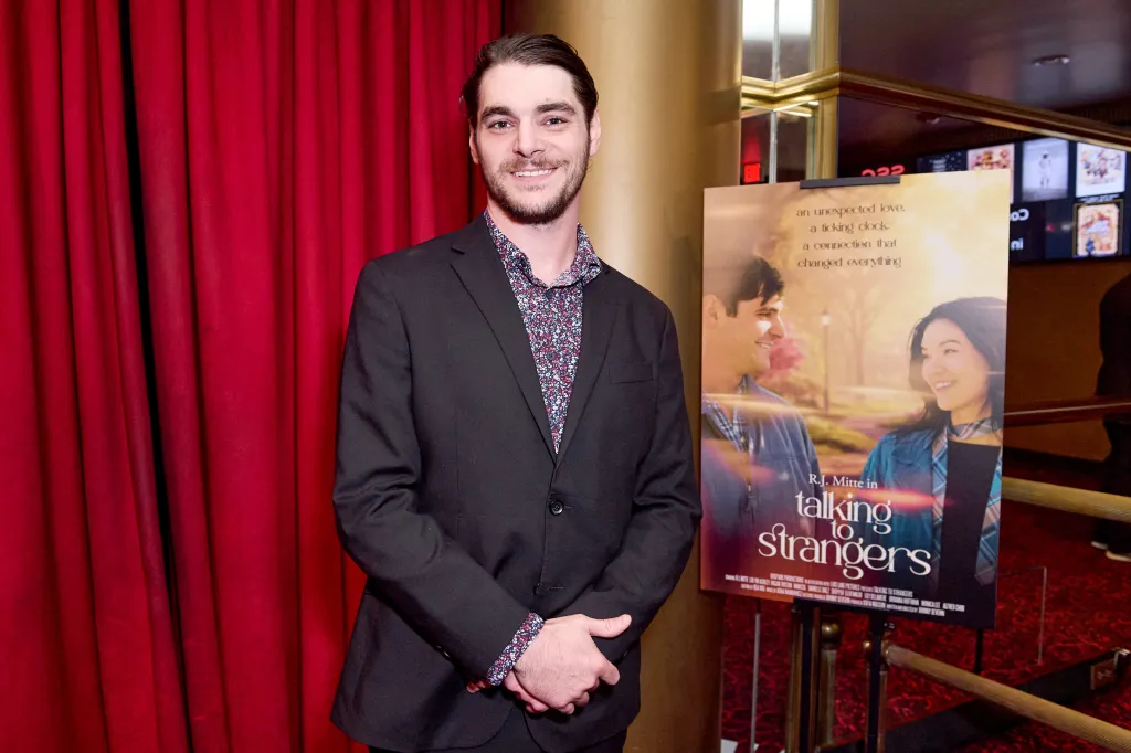 RJ Mitte standing next to a poster for 
