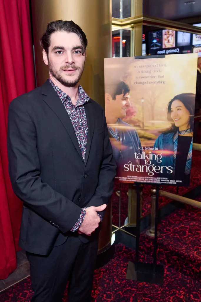 RJ Mitte stands beside a poster for 