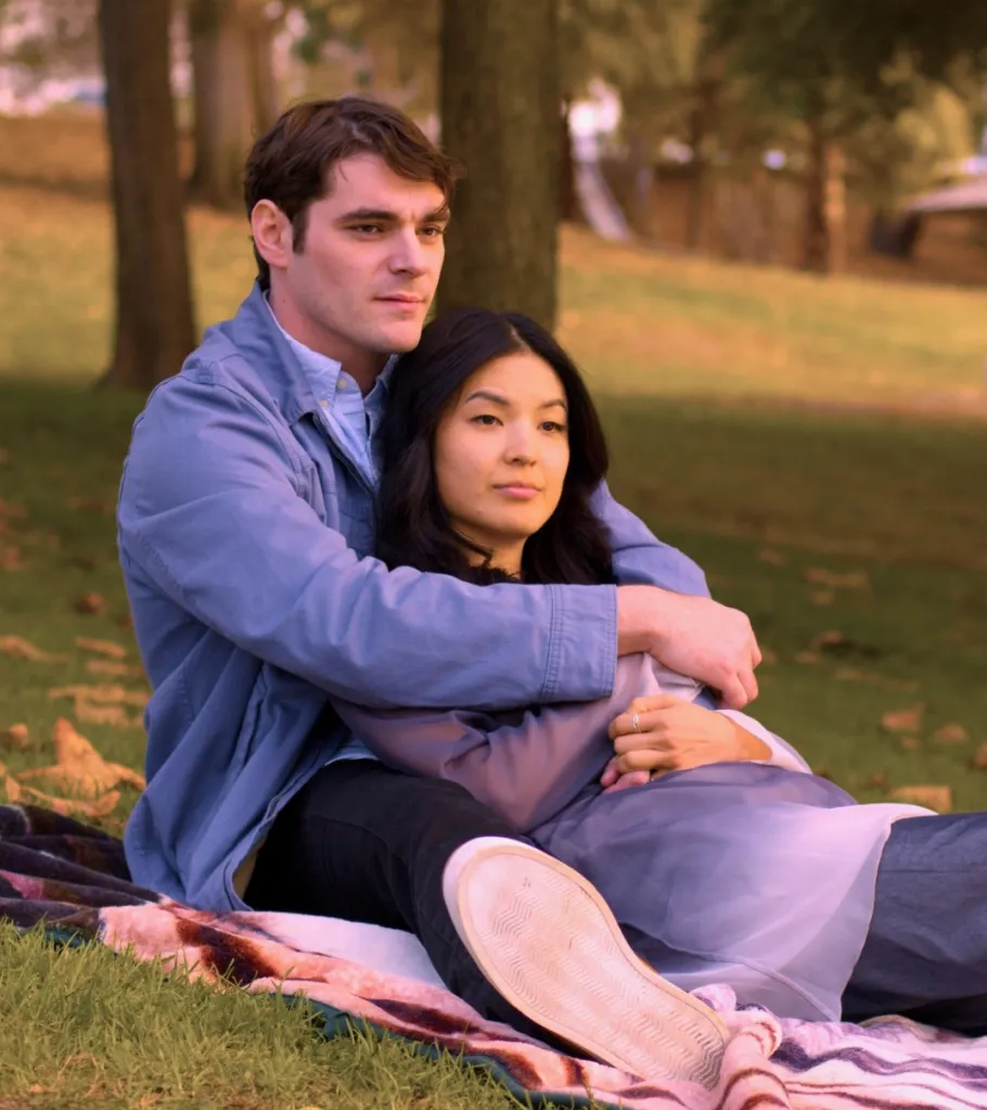 RJ Mitte and another actor sitting on a blanket in a park, from the movie 