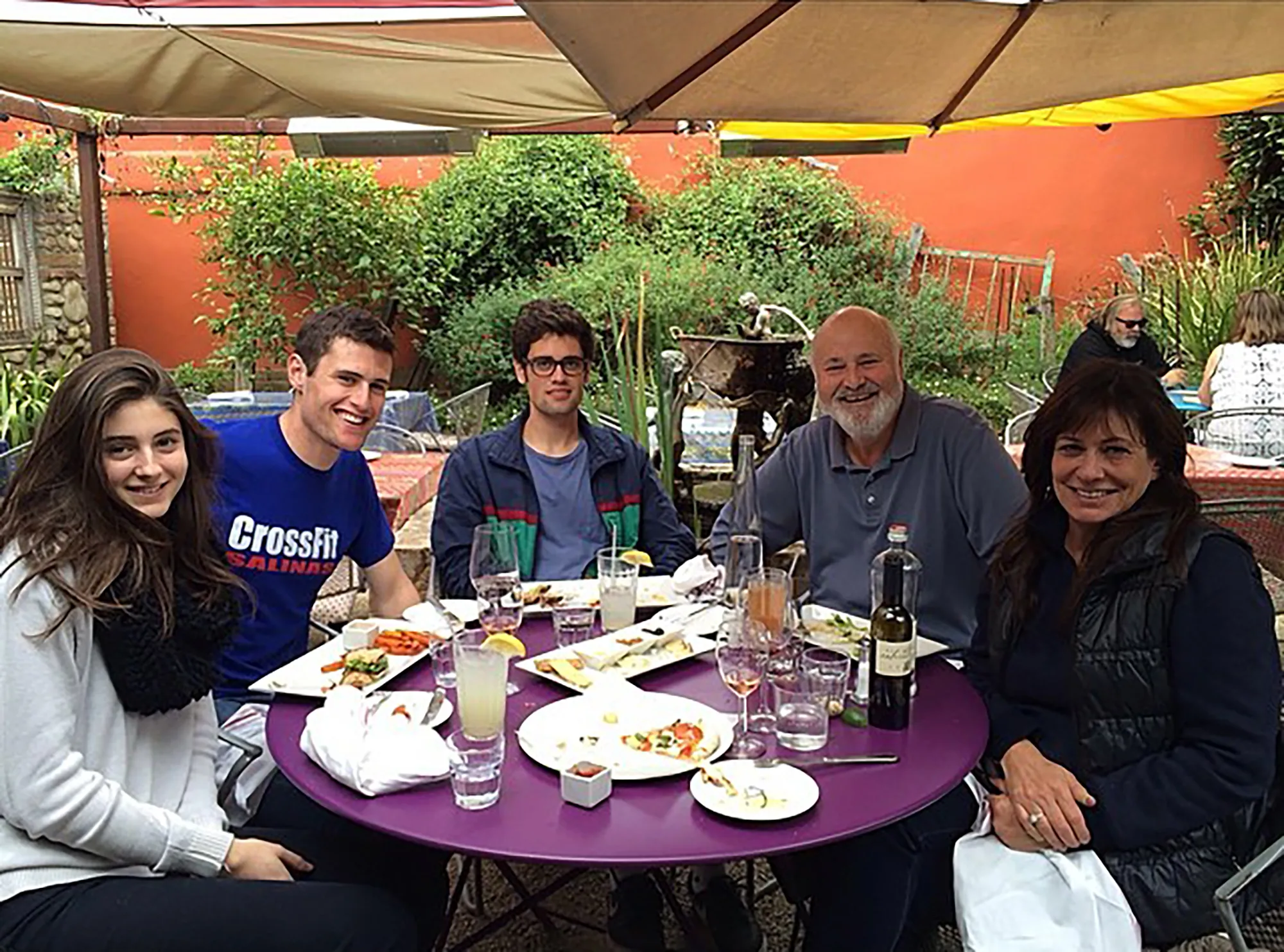 Rob Reiner and family seated at an outdoor restaurant table.