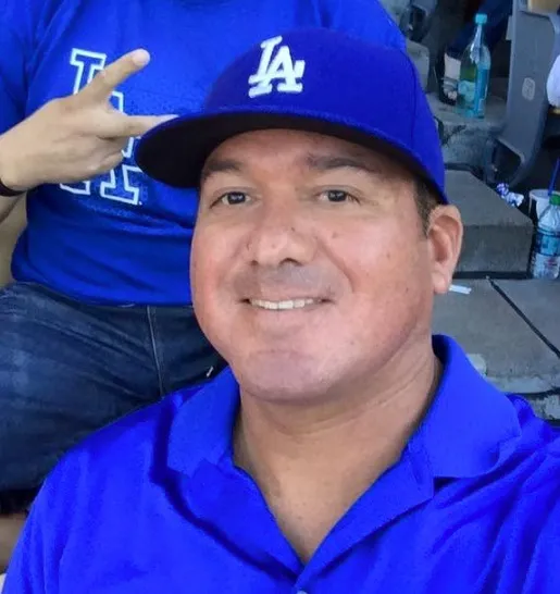 Robert Rocha smiling and wearing a blue polo and a blue LA Dodgers baseball cap.