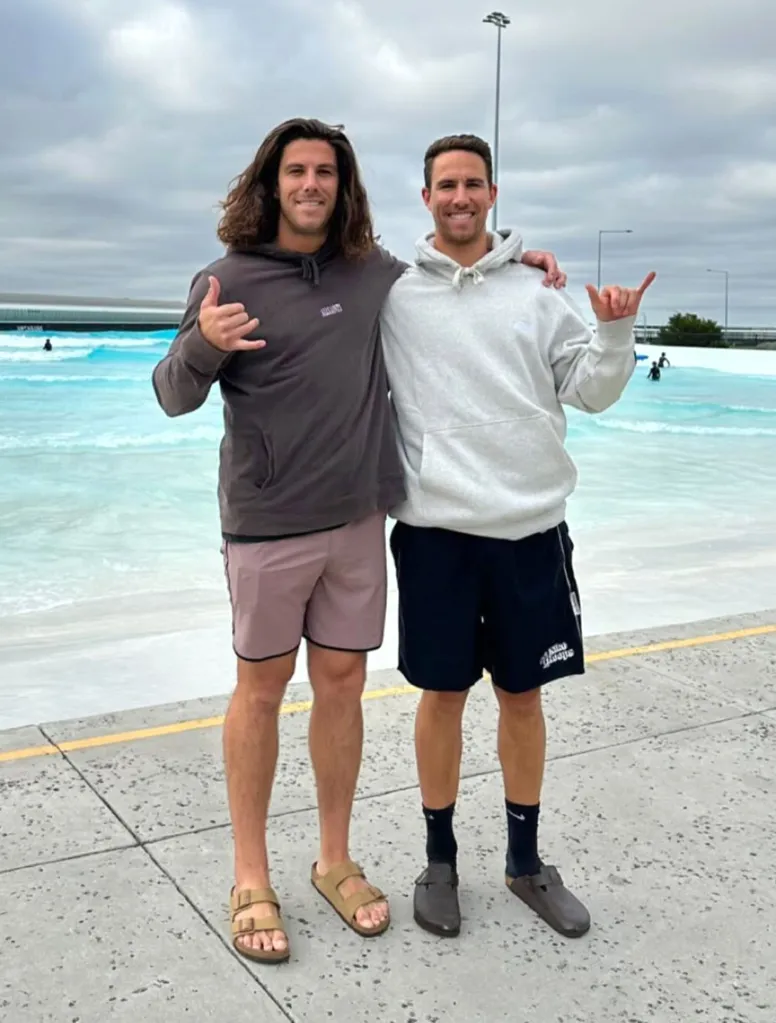 Brothers Callum and Jake Robinson posing together in front of a wave pool.