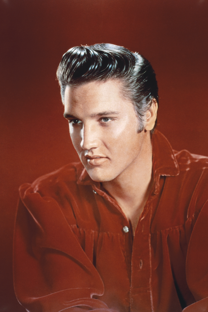 Portrait of rock and roll musician Elvis Presley in a red shirt.
