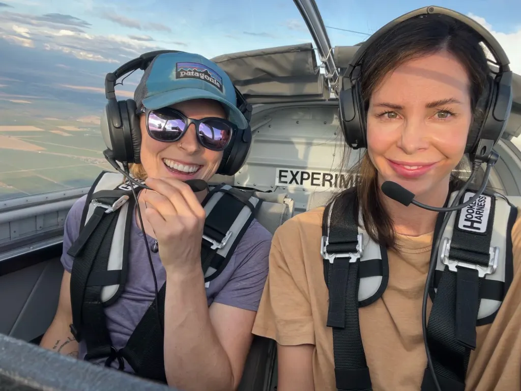 Rosie Bates poses in the passenger seat of an airplane with another person.