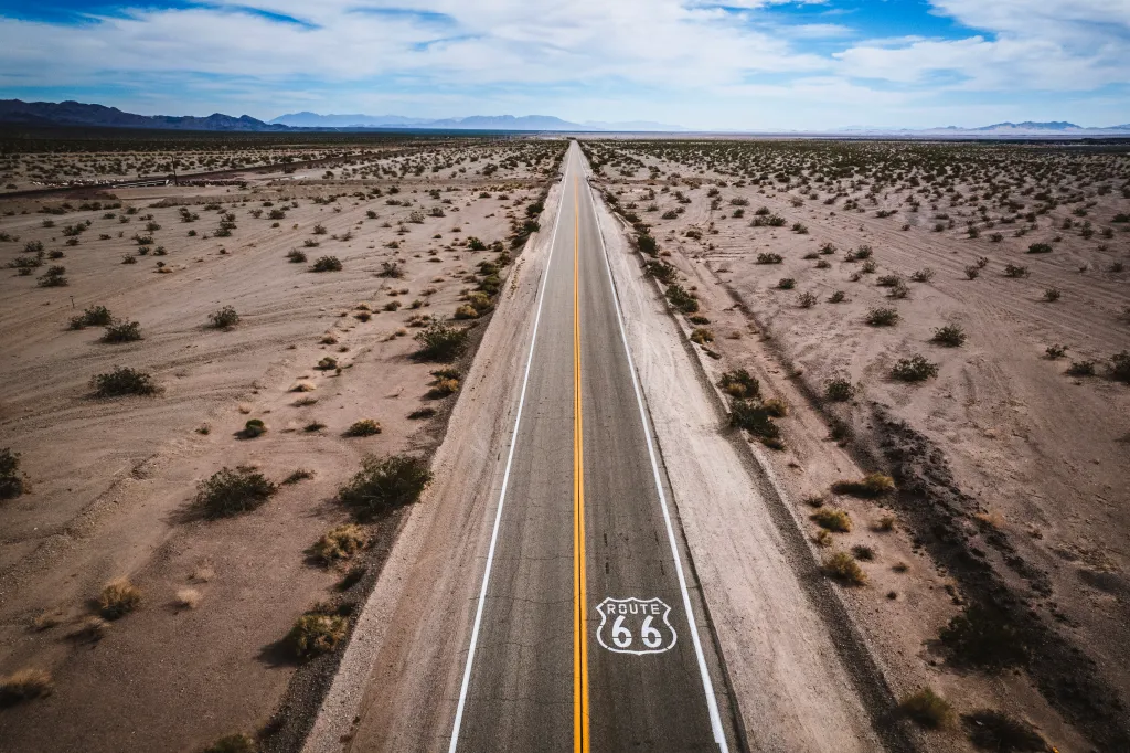 Aerial view of Route 66 stretching straight through the vast, flat landscape of the Mojave Desert.