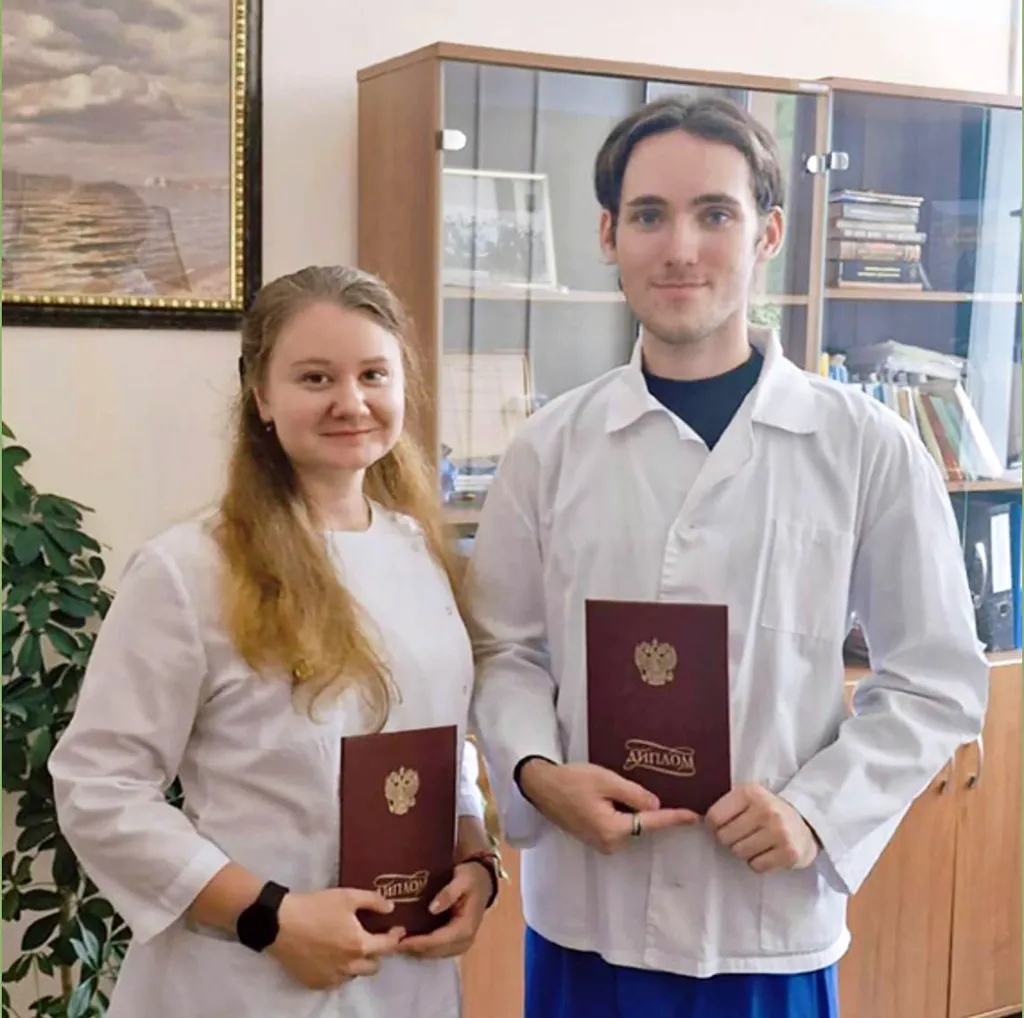 Daria Shipilova and a colleague holding diplomas in a lab setting.