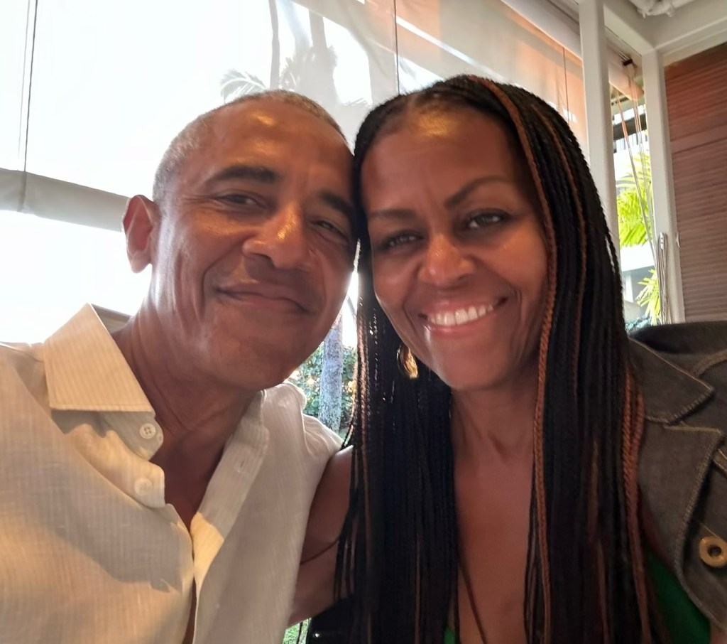 Barack and Michelle Obama smiling together, cheek to cheek.