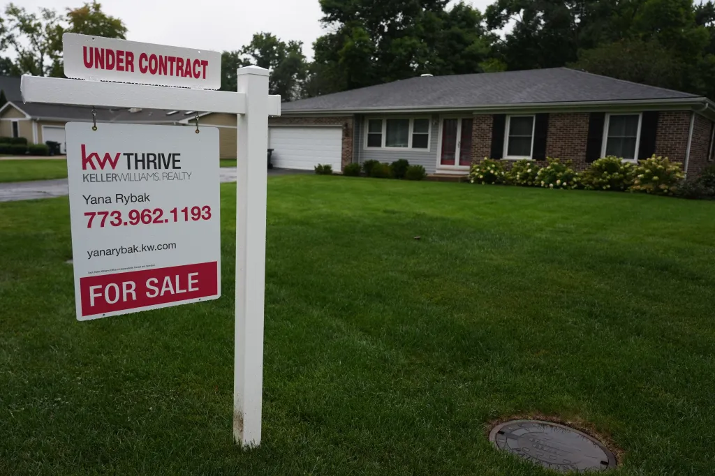 A for-sale sign stands in the front yard of a single-story home.