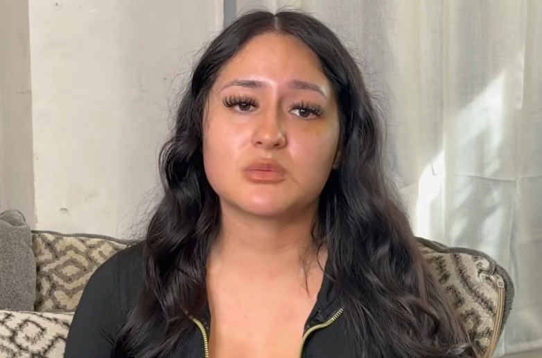 Samantha Baez-Vargas with long dark hair, wearing a black top, seated in front of a patterned couch.