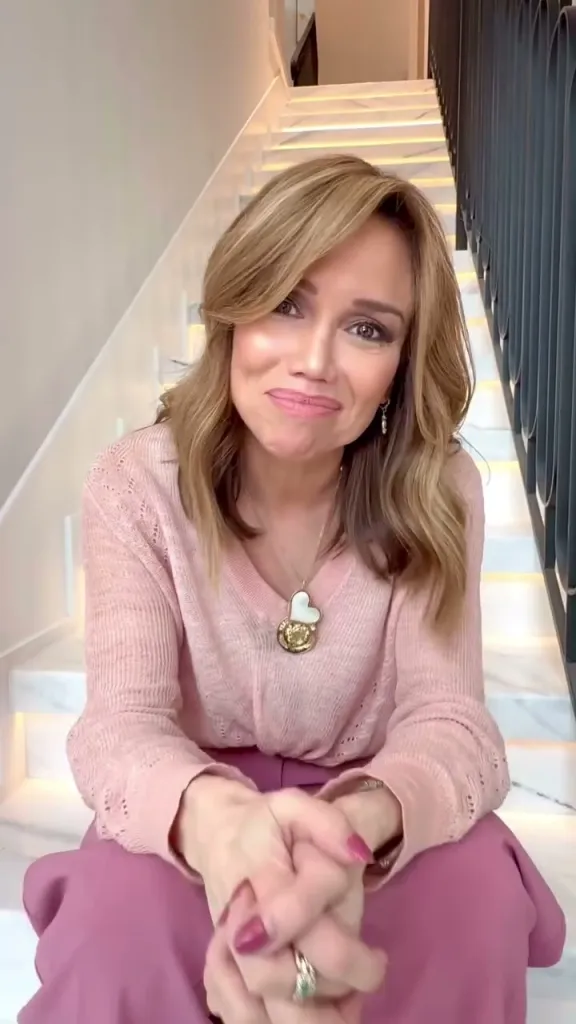 Sara Gore sitting on a staircase with a light-up handrail, wearing a pink sweater and purple pants.