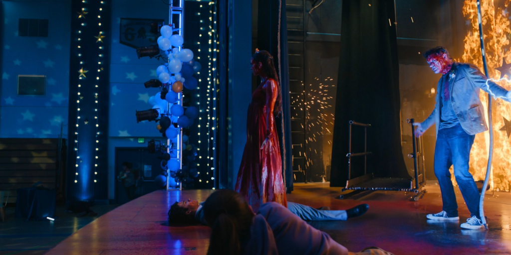Screenshot of Matthew Lillard as a bloody character standing on a stage next to a fire.