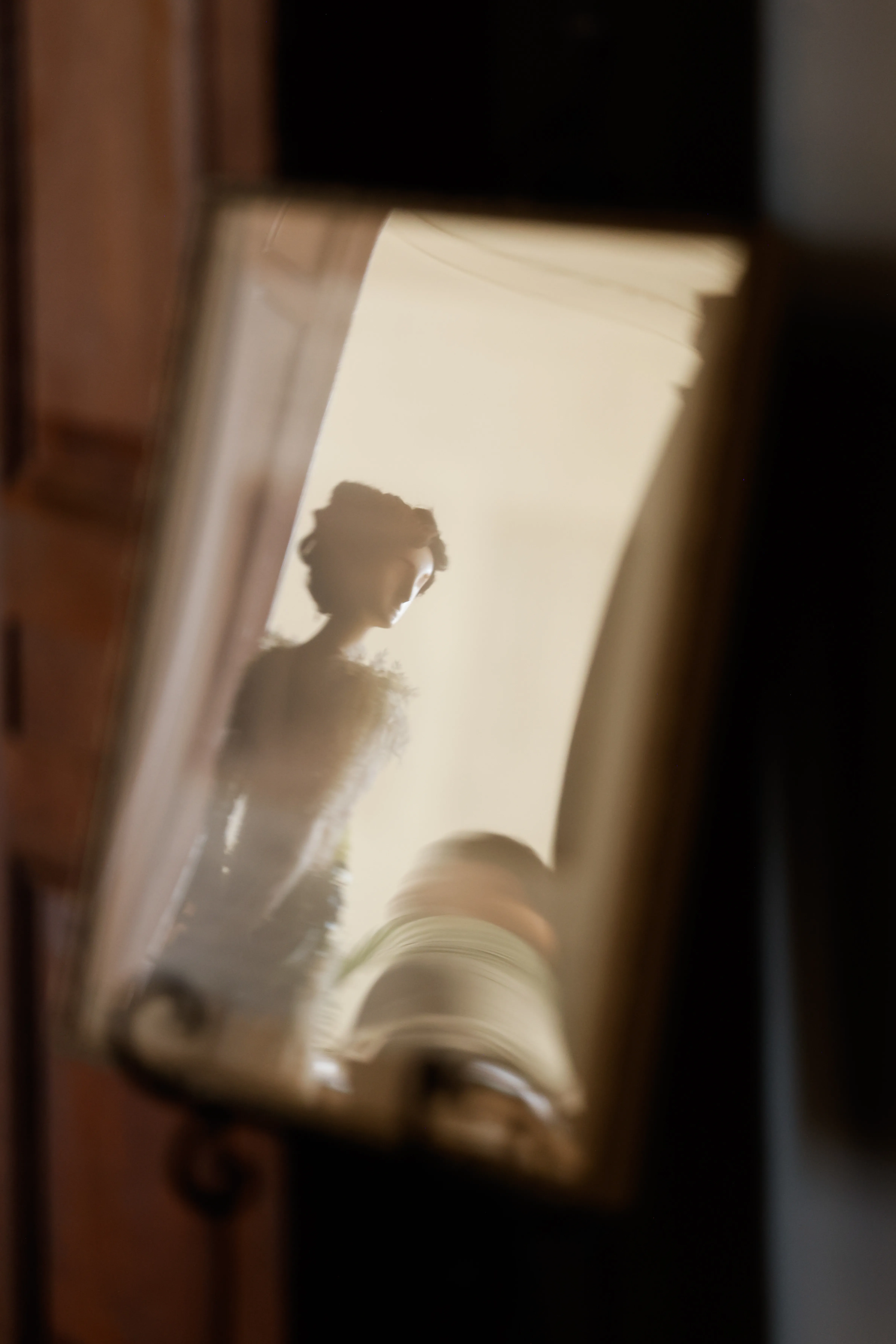 A sculpture of a woman is reflected in a sign as workers build their pieces for Fleurs de Villes.