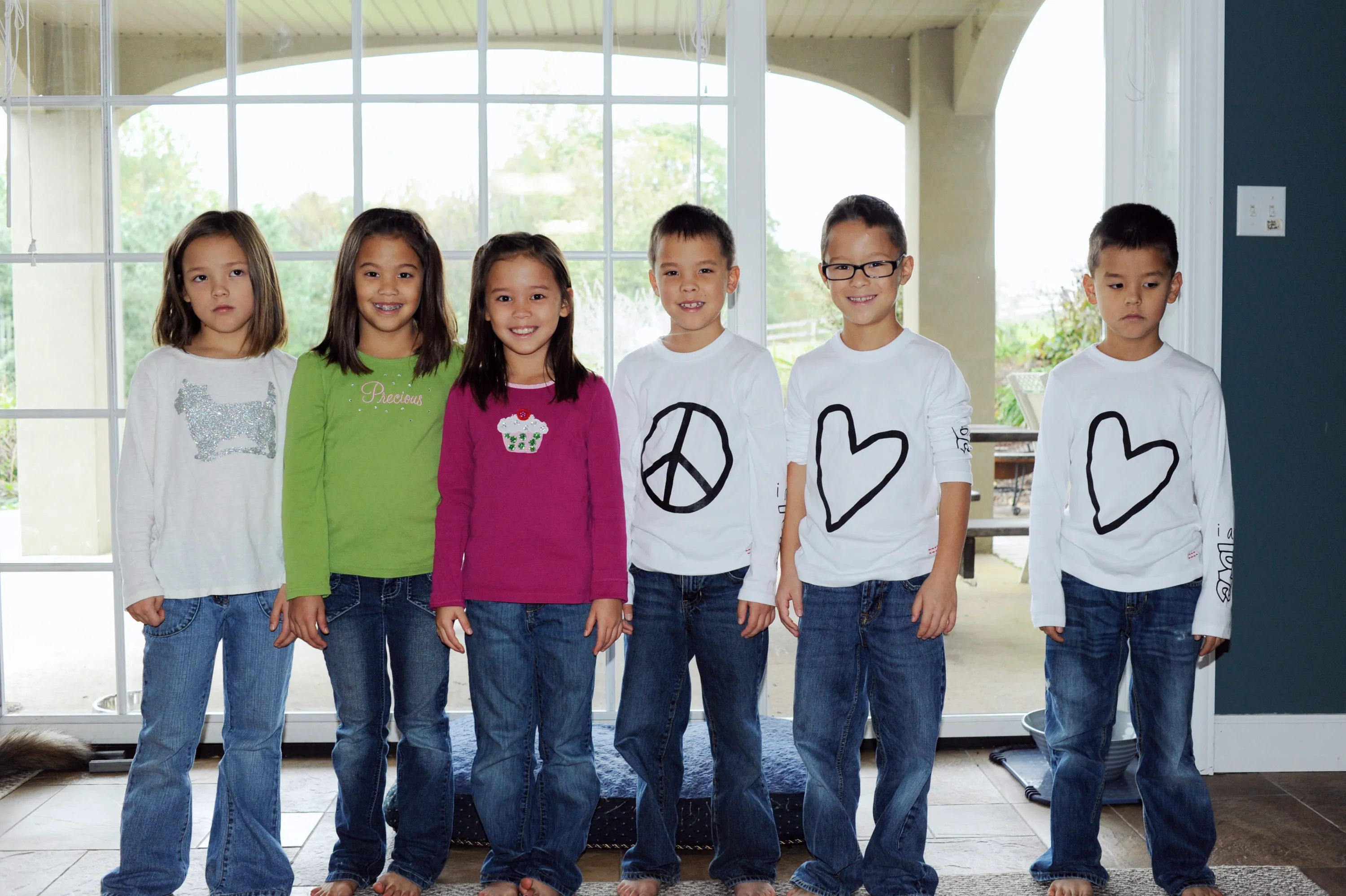 Alexis, Hannah, Leah, Joel, Aaden, and Collin Gosselin standing in a row in front of a window.