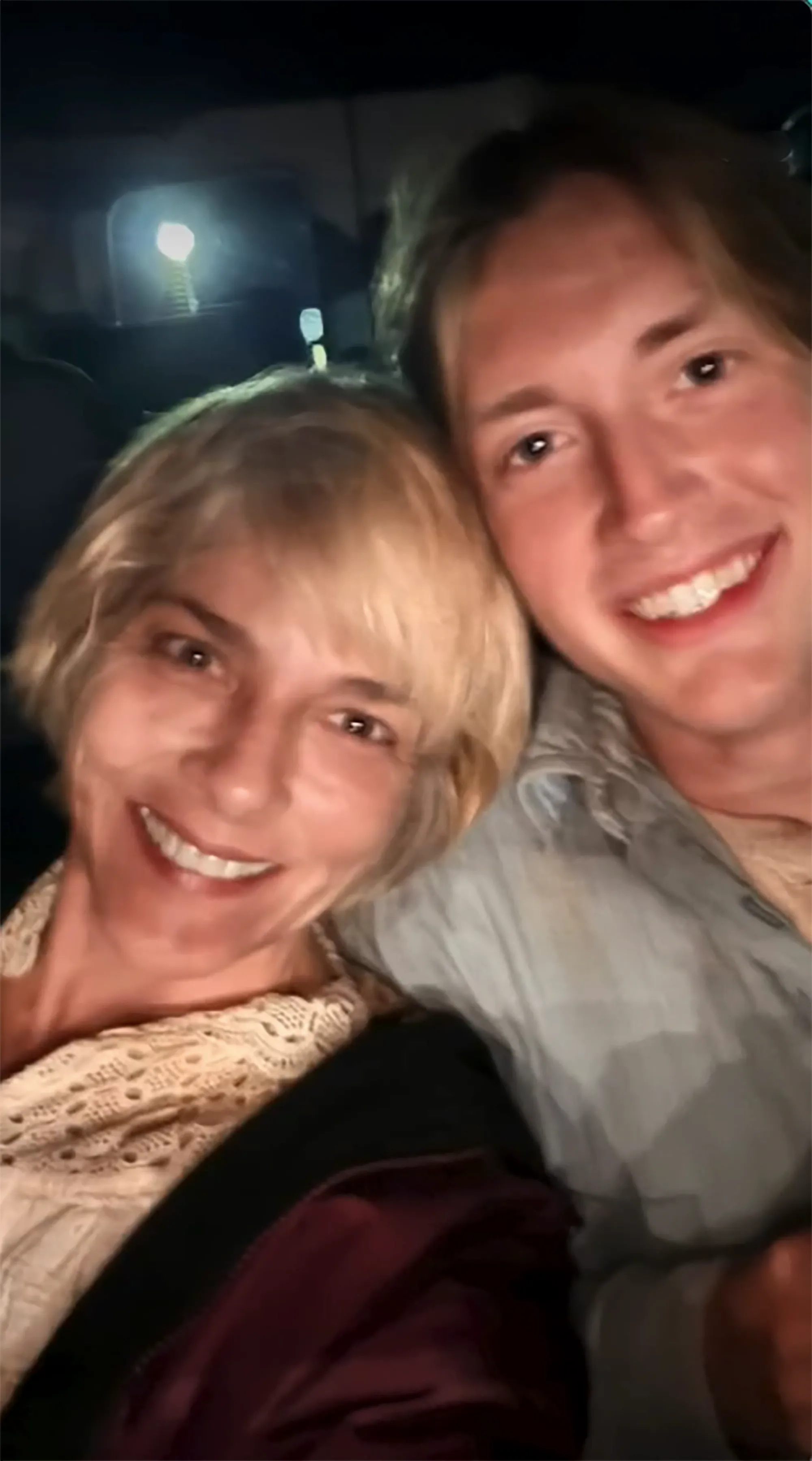 Selma Blair and a young man smiling closely together in a vehicle, with no visible signs of chaos.