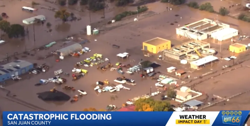 Aerial view of severe flooding surrounding buildings and vehicles in San Juan County, New Mexico.
