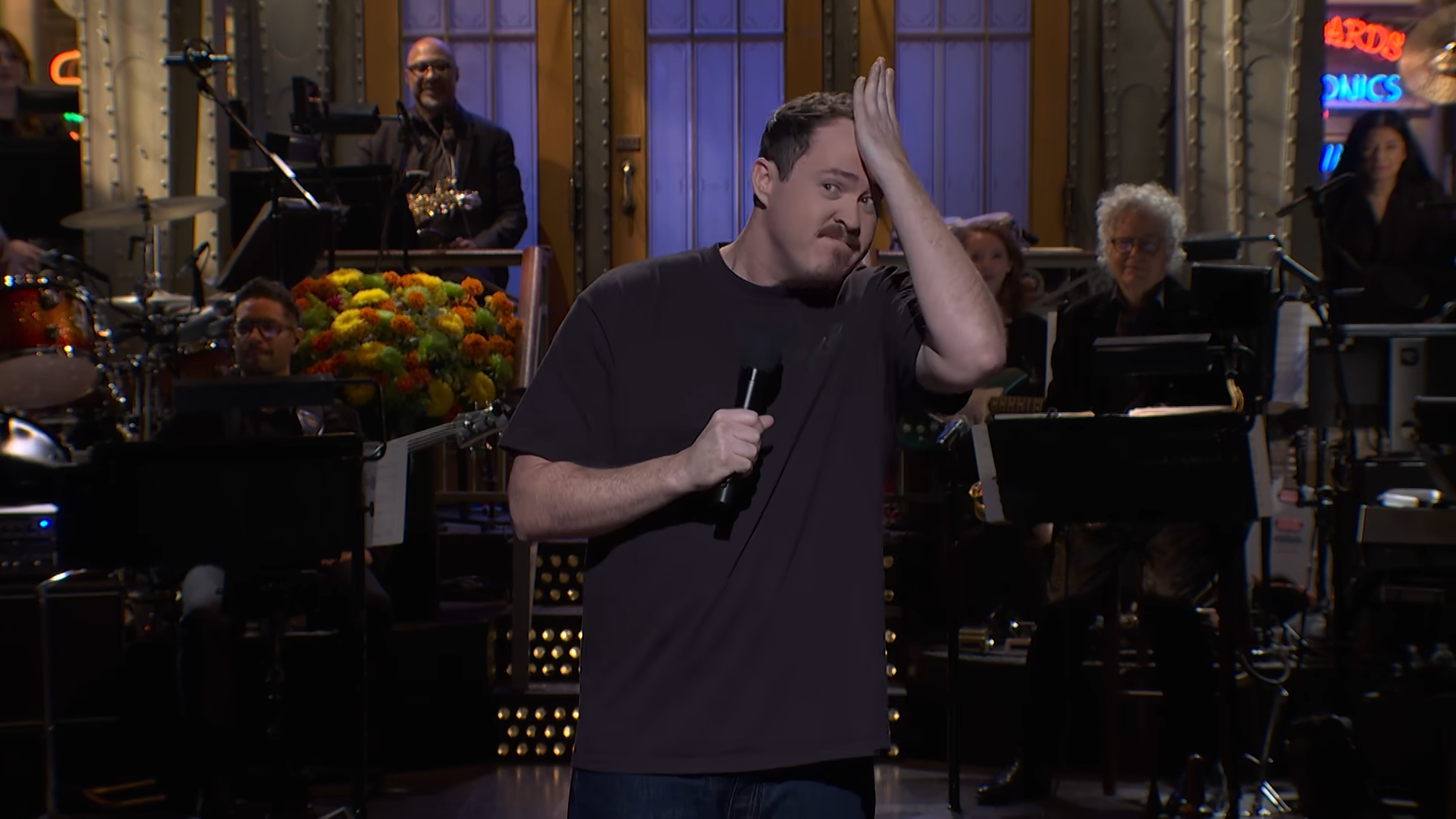 Shane Gillis on stage, holding his head in hand on Saturday Night Live.