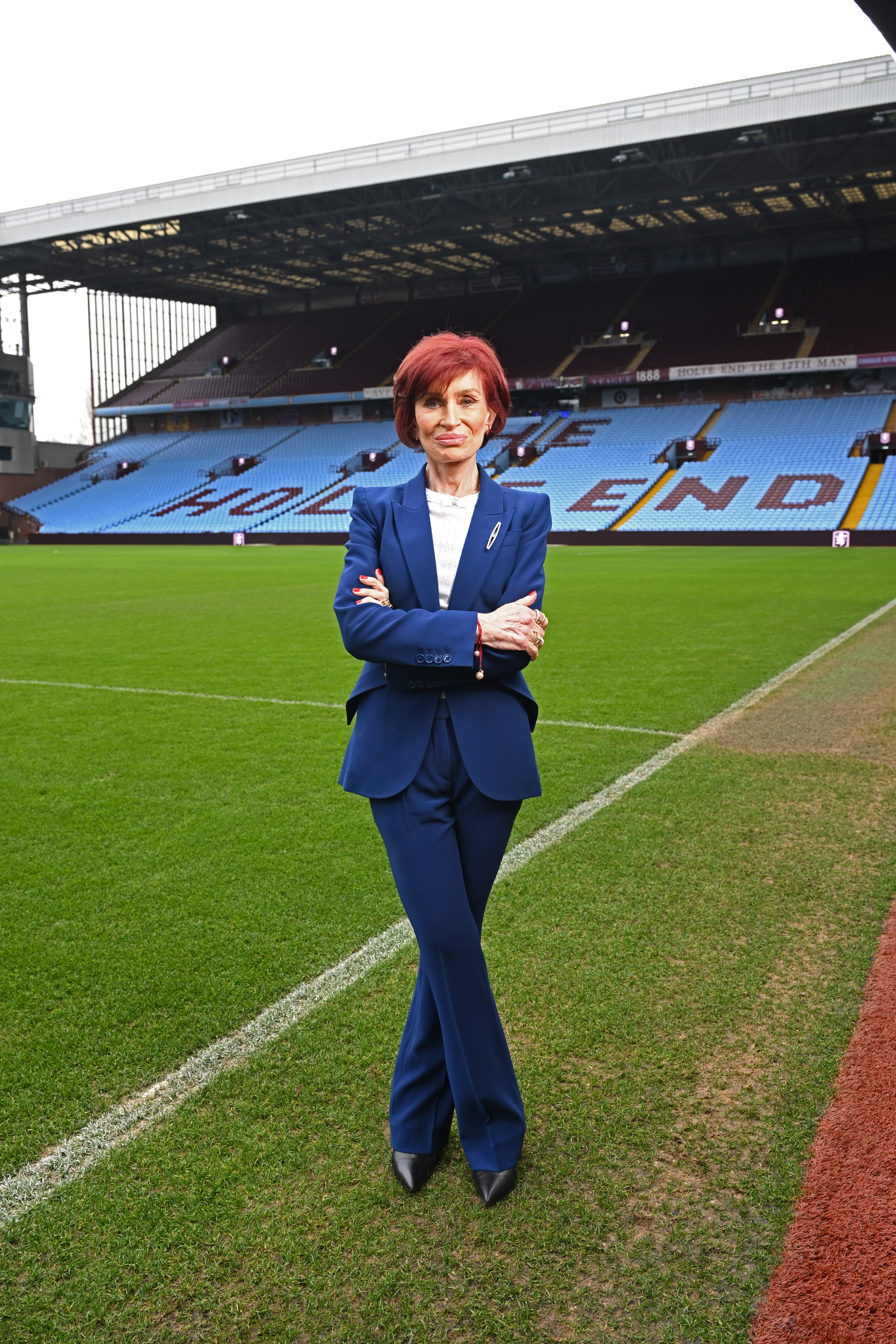 Sharon Osbourne standing on the pitch at Villa Park with her arms crossed.