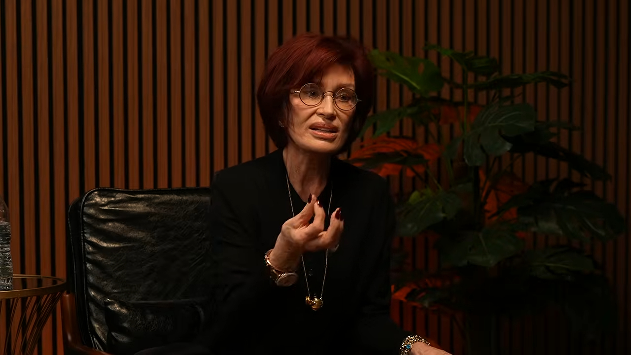 Sharon Osbourne sitting in a black chair, gesturing with her hands while speaking.