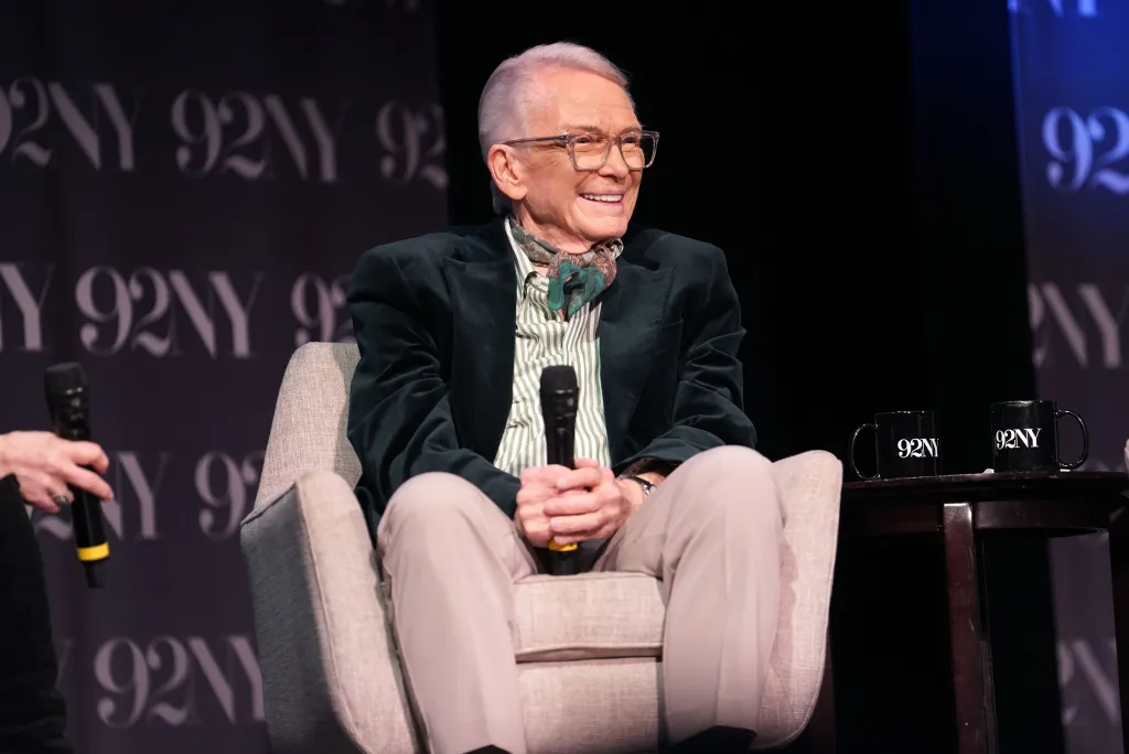Bob Mackie attends the Met Gala at the Metropolitan Museum of Art in a tuxedo with a polka-dot bow tie in front of a pink floral wall.
