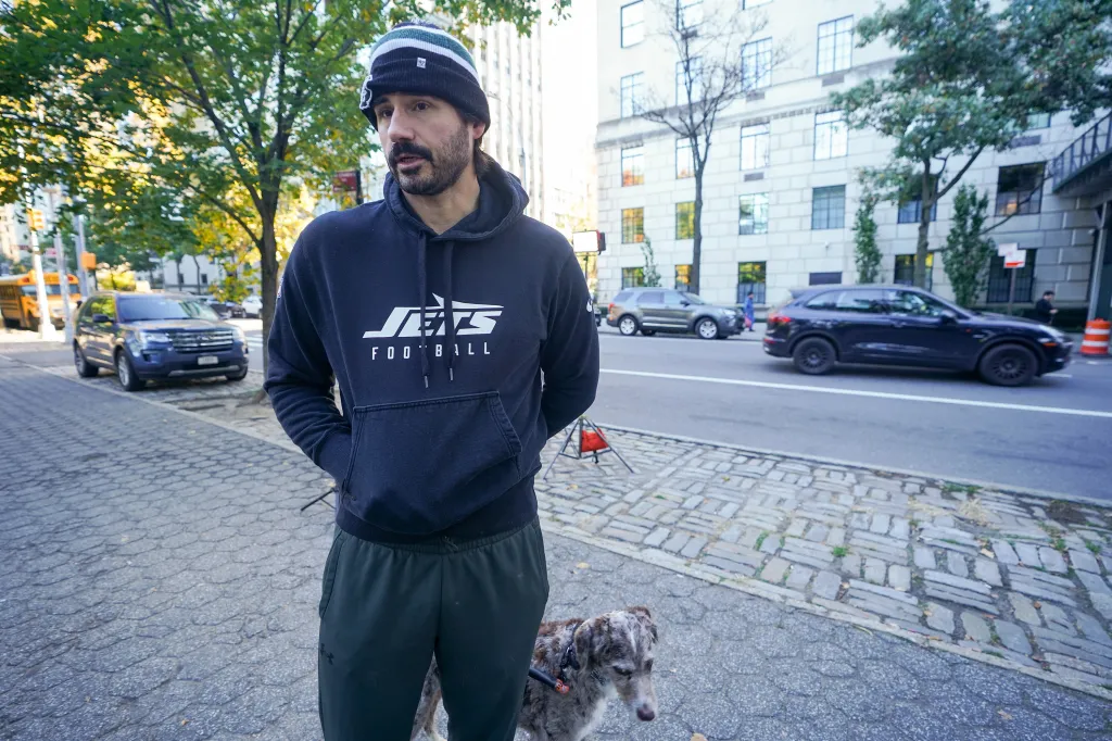 Jetmir Shala stands on a city street with his dog.