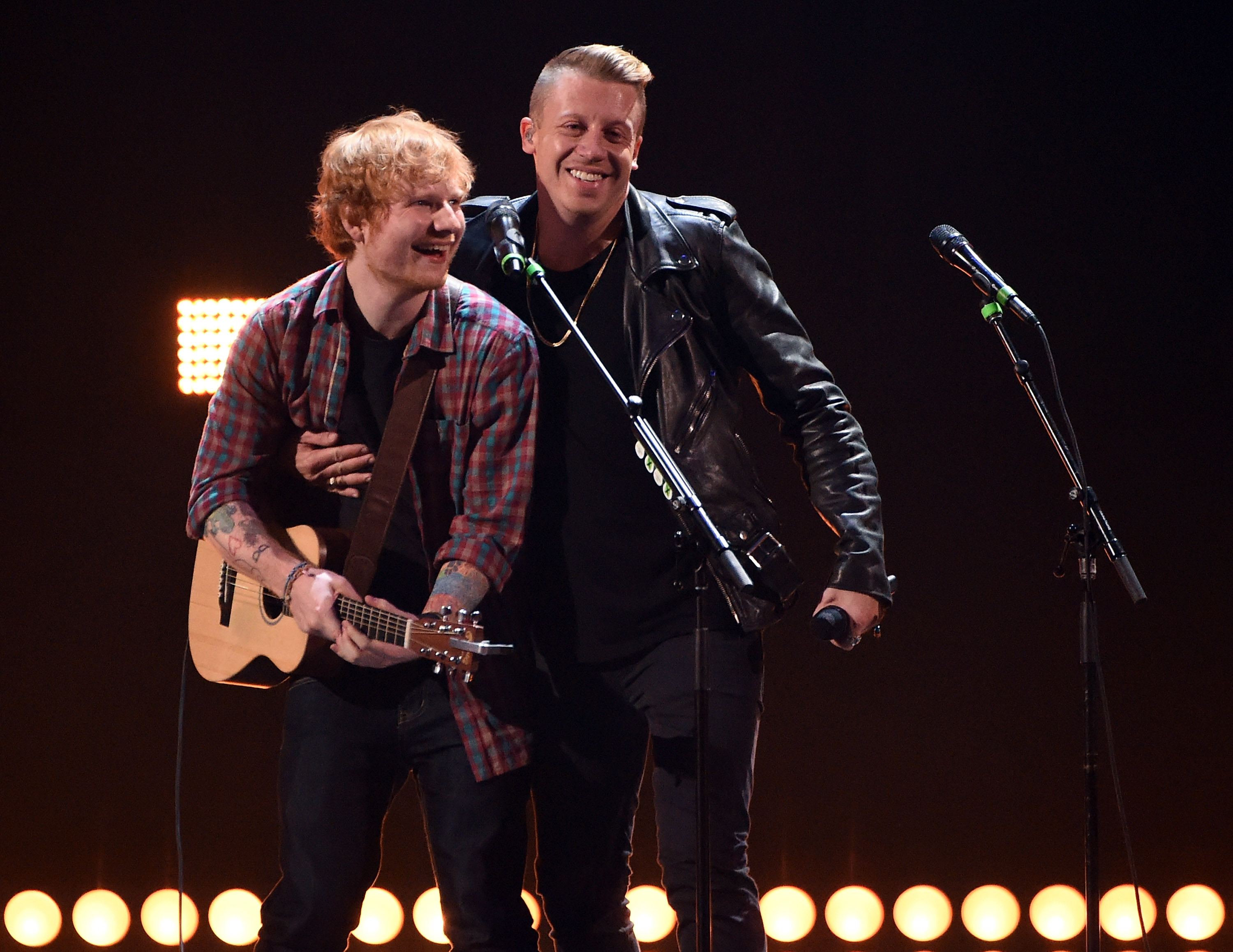 Singer/songwriter Ed Sheeran and rapper Macklemore perform on stage.